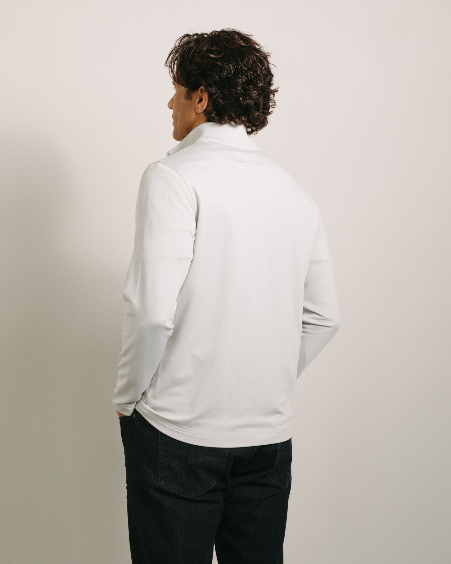 Person wearing a light fog gray quarter zip and dark pants against a plain background