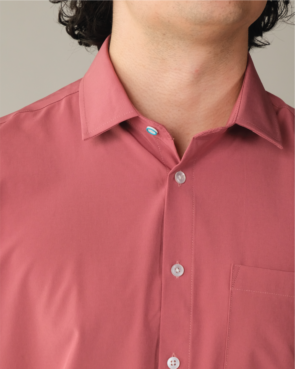 Detail shot of man wearing an adobe red shirt. Top button has blue ring
