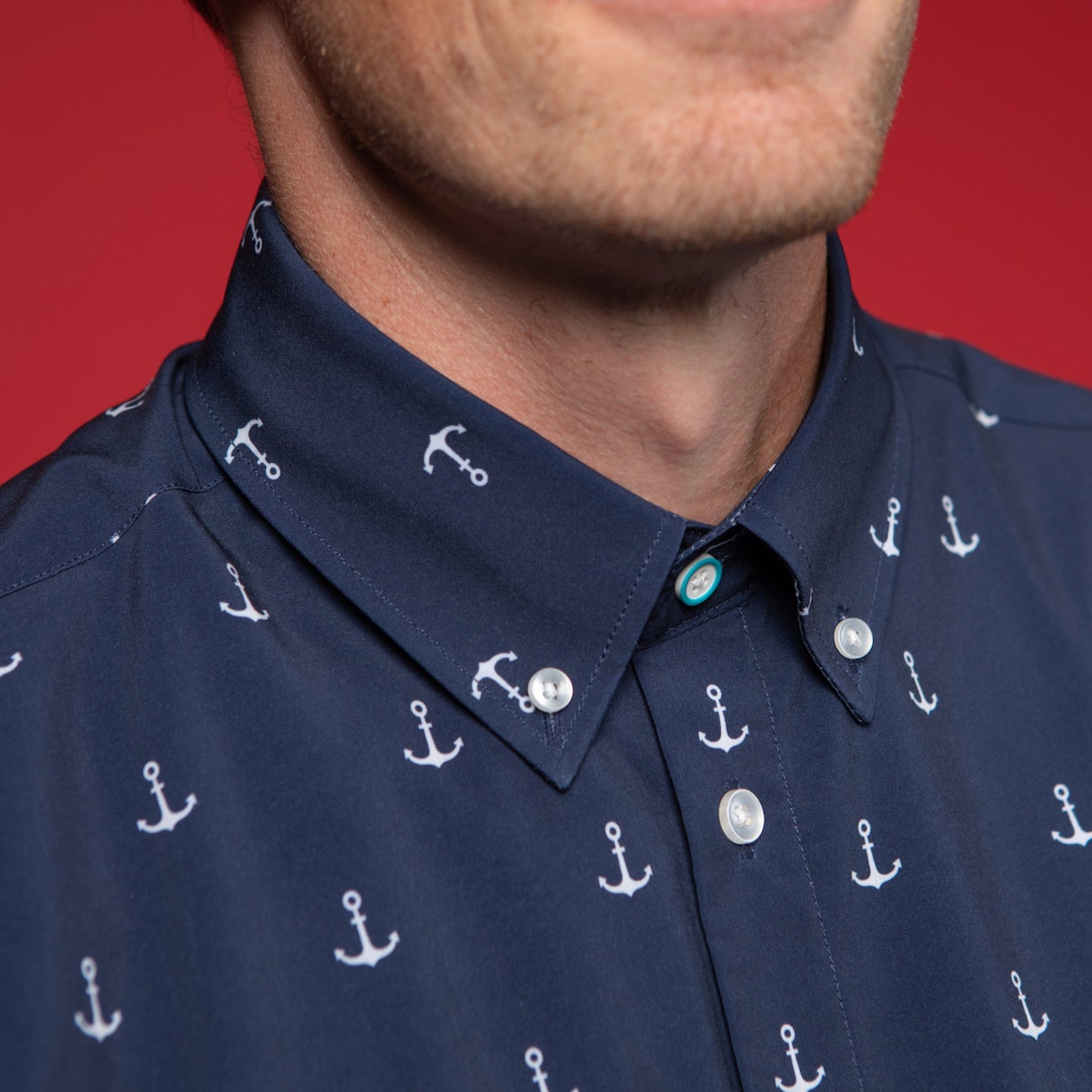 Man wearing Navy shirt with white anchors. Top button has blue ring.