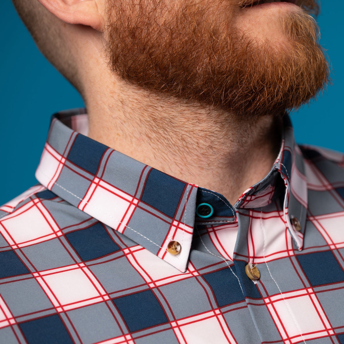 Man wearing white and Navy shirt w/ Red Accents. Top button has blue ring.
