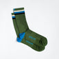 Green dress socks with light blue &Collar logo, light blue heel, and blue, black, and white strips across the top of the sock.