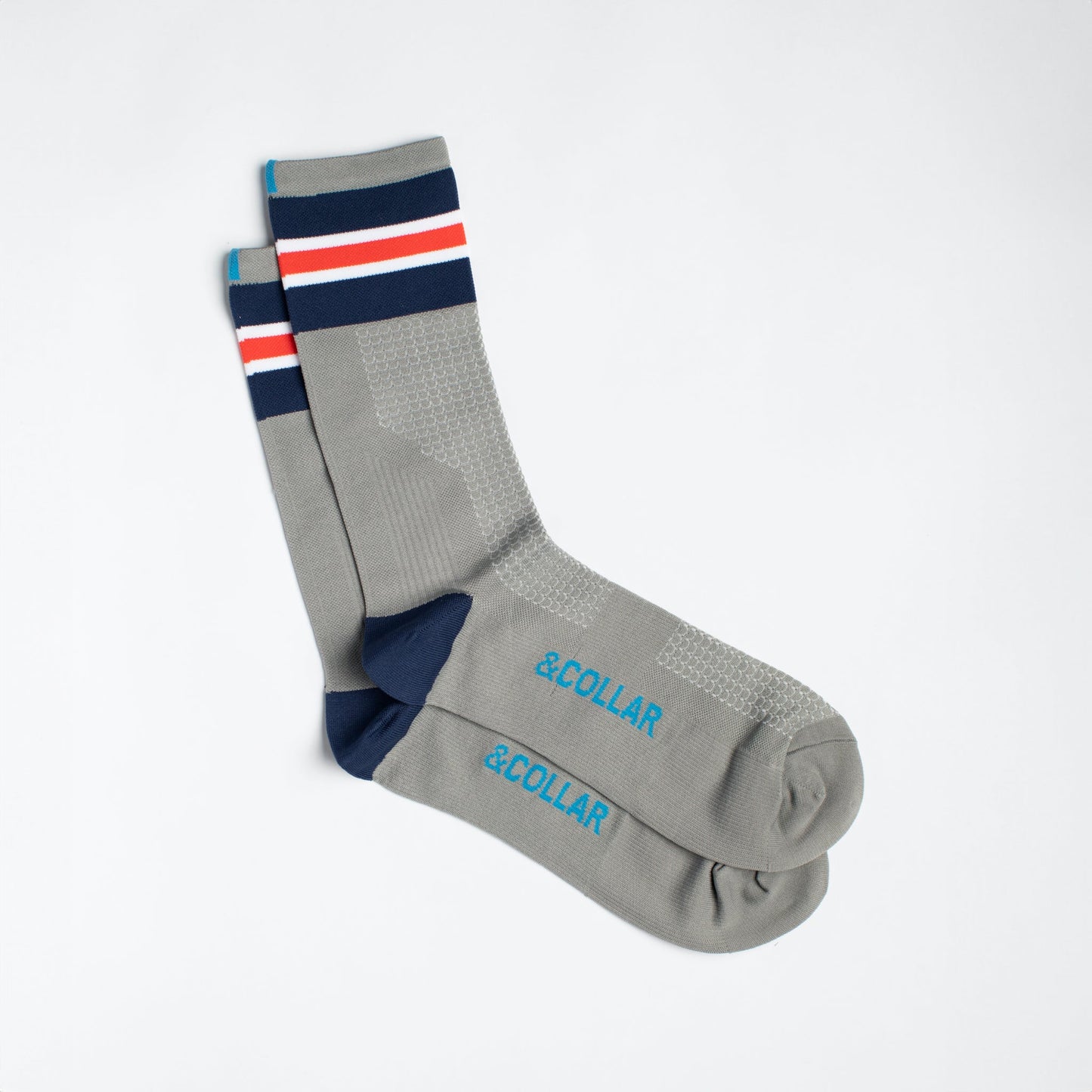 Grey dress socks with light blue &Collar logo, dark blue heel, and dark blue, red, and white stripes across the top of the sock.