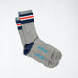Grey dress socks with light blue &Collar logo, dark blue heel, and dark blue, red, and white stripes across the top of the sock.