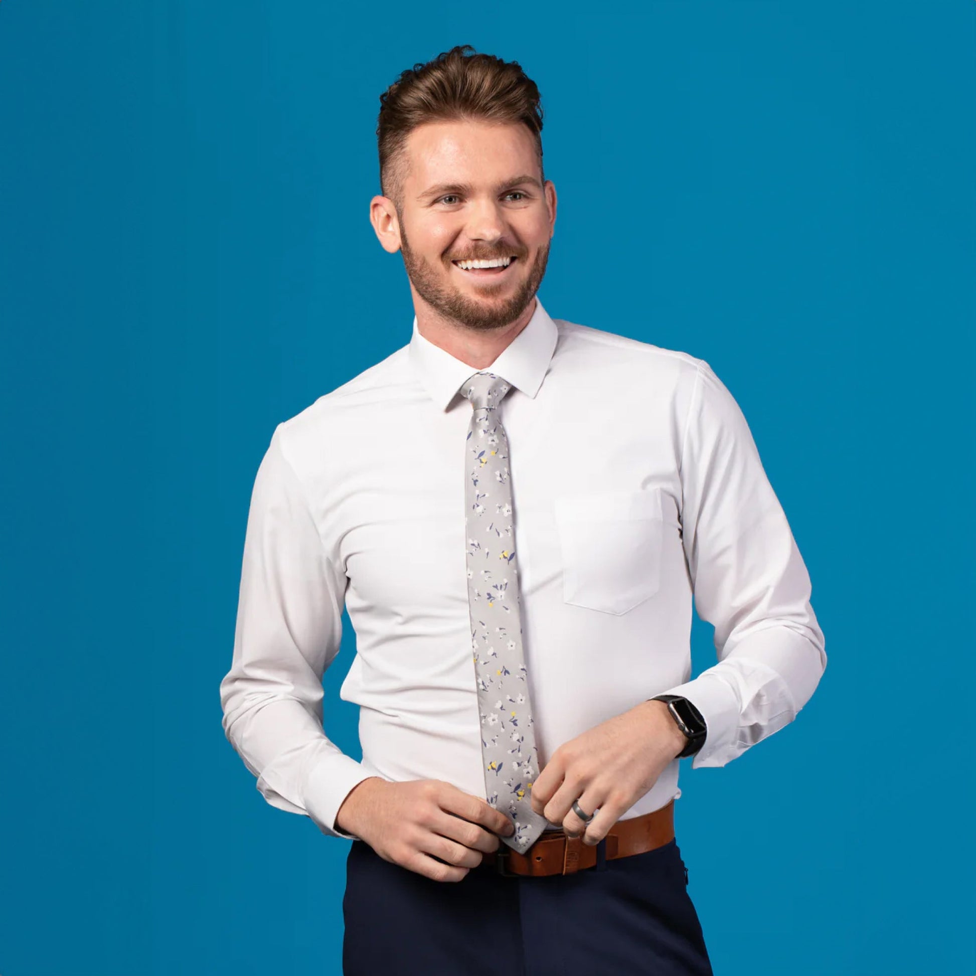 Grey tie with blue, yellow, and white floral patterned design on white dress shirt